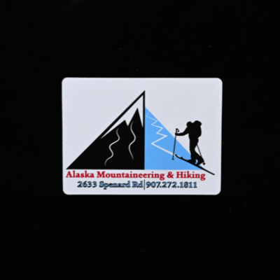 A rectangular sticker with a skier hiking up a mountain for 'Alaska Mountaineering & Hiking'
