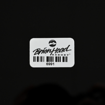 A white rectangular sticker for 'Brian Head' with a barcode and ID number underneath the company logo