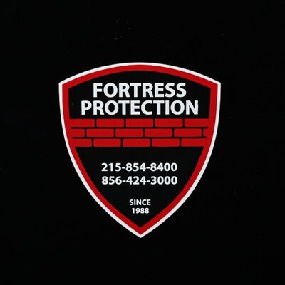 A black badge sticker that's more shield shaped that reads 'Fortress Protection'