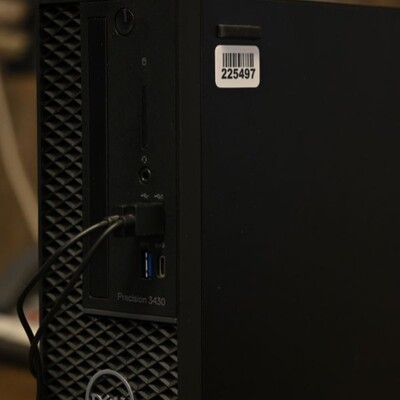 A dell pc tower with a small barcode label on the side of it to be able to identify the unit.
