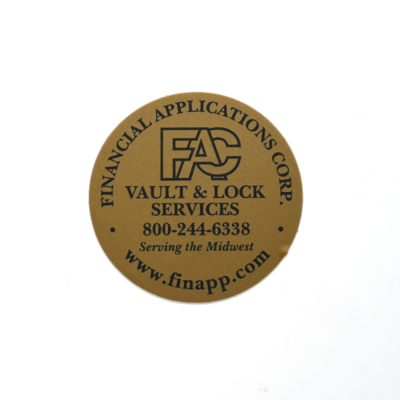 A circular sticker that is finished it what looks almost gold with fine text that reads 'Vault & Lock Services'