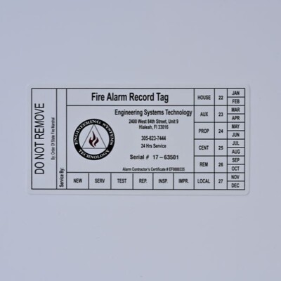 A white rectangular sticker with black text that's a Fire Alarm Record Tag