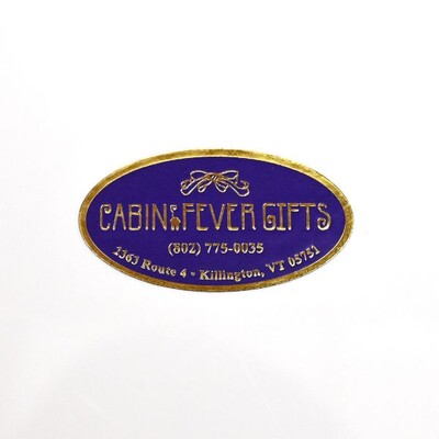 A purple oval sticker with gold text and border that read 'Cabin Fever Gifts'